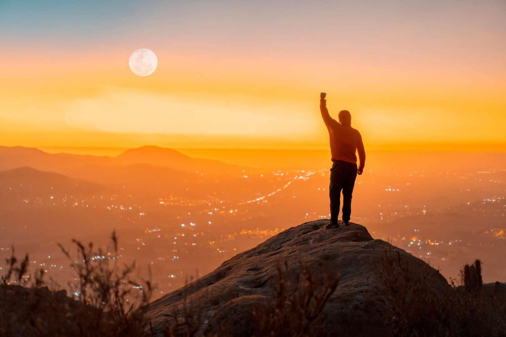 A man standing on the top of the mountain with hand up